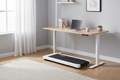 Slim white walking treadmill under a standing desk in a bright home office